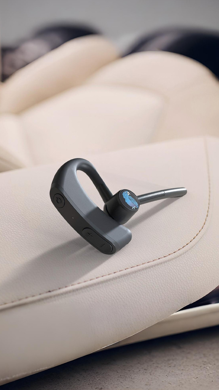 Close-up of the BlueParrott M500-XT Bluetooth device resting on a vehicle armrest.